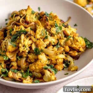 Curry roasted cauliflower salad with chickpeas, cashews, red onion and cilantro in a bowl.