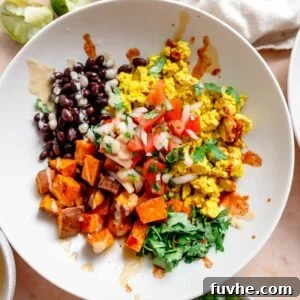 Breakfast burrito bowl with cilantro, tofu scramble, black beans, roasted sweet potato, chipotle sauce and hot sauce drizzled over top.