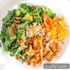 A colorful Tofu Broccoli Bowl with creamy sauce, kale, carrots, and crispy coconut bacon.