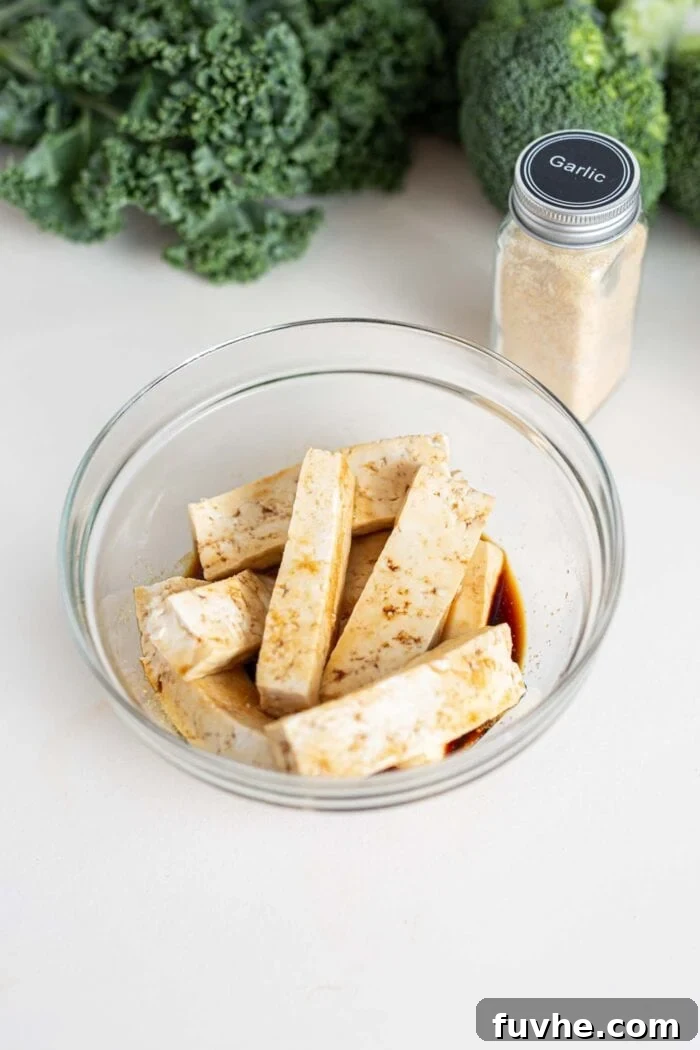 Green Harvest Bowl 4 Slices of firm tofu marinating in a shallow bowl with a savory soy sauce mixture.