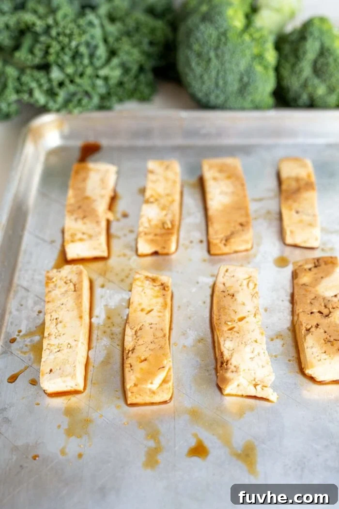 Green Harvest Bowl 6 Marinated tofu slabs neatly arranged on a baking sheet, ready for baking to golden perfection.