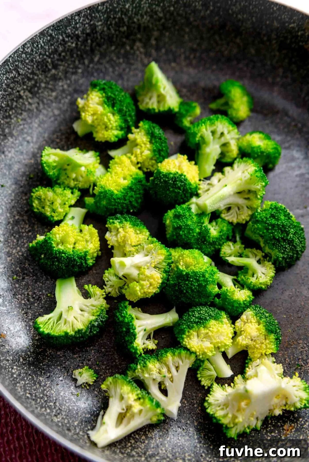 Green Harvest Bowl 8 Bright green chopped broccoli florets in a large stainless steel skillet, ready for steaming.