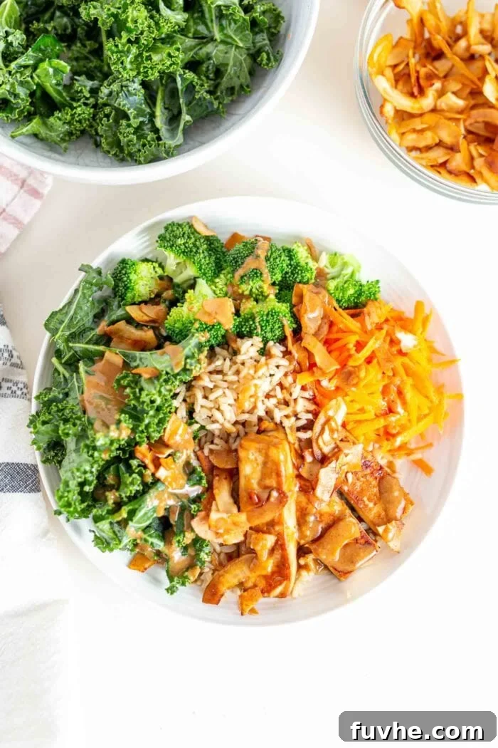 Green Harvest Bowl 9 A fully assembled Tofu Broccoli Bowl, featuring a colorful array of tofu, sauce, kale, broccoli, carrot, and coconut bacon.