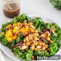 A kale salad topped with squash, chickpeas, cranberries, hemp seeds and walnuts.