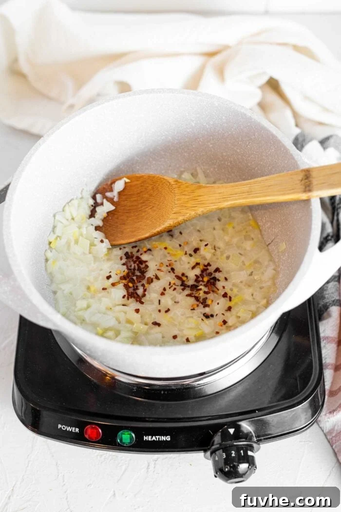 Fragrant Vegan Thai Green Curry 4 Onions and garlic gently cooking in a large soup pot with a wooden spoon, releasing their fragrant aromas.