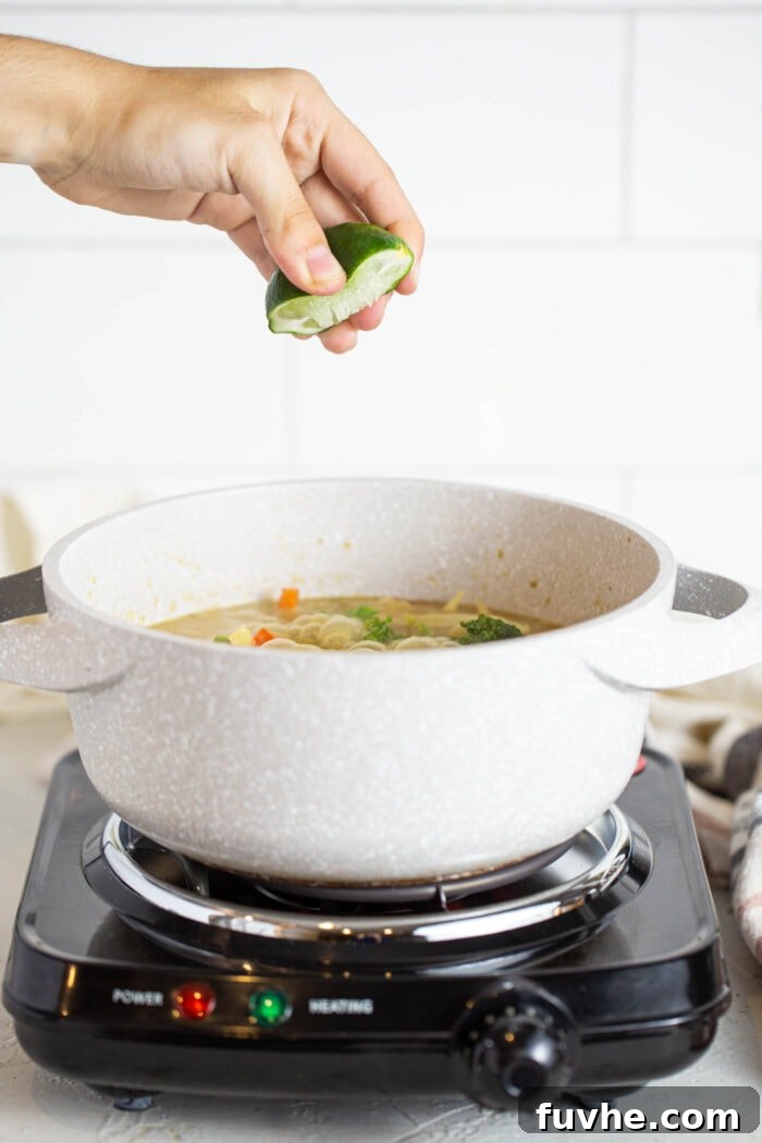 Fragrant Vegan Thai Green Curry 7 Fresh lime juice being squeezed into a pot of green curry, adding a bright, zesty finish.