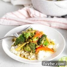 Vegetable green curry on top of rice in a bowl.