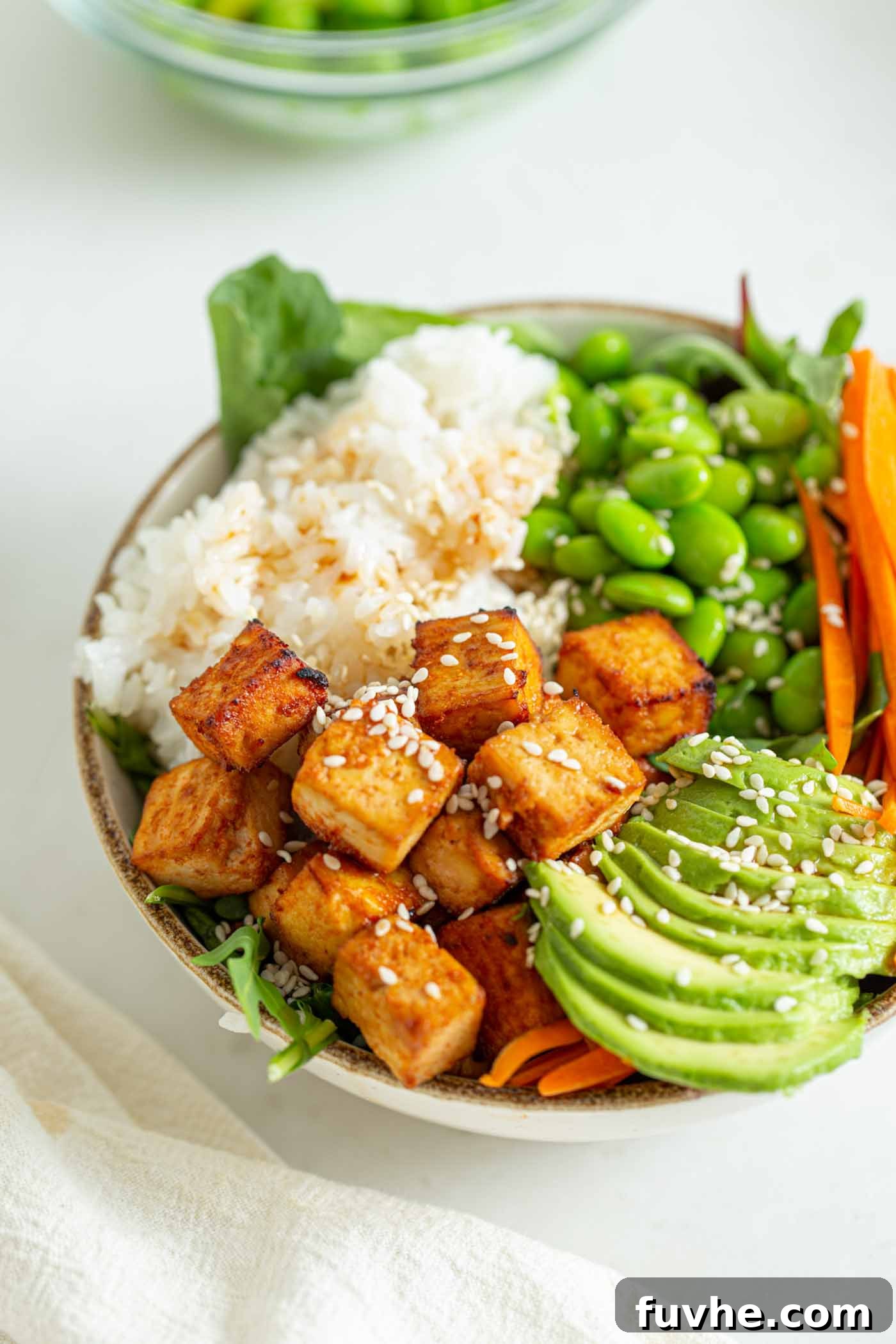 Crisp baked tofu in a bowl with avocado, rice and edamame.