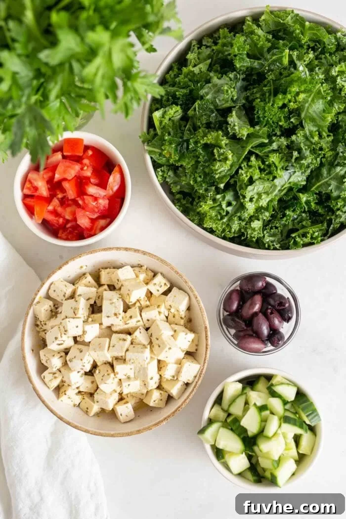 Tofu, olives, chopped kale, cucumber and tomato in bowls.