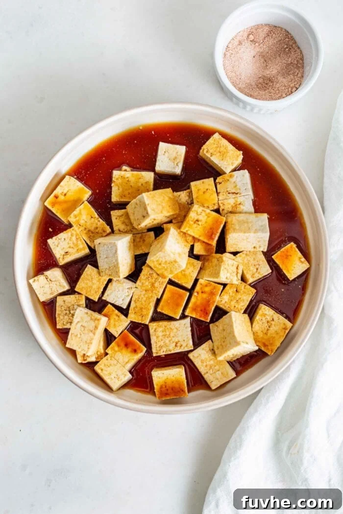 Cubed tofu mixed in a bowl with a soy sauce marinade.