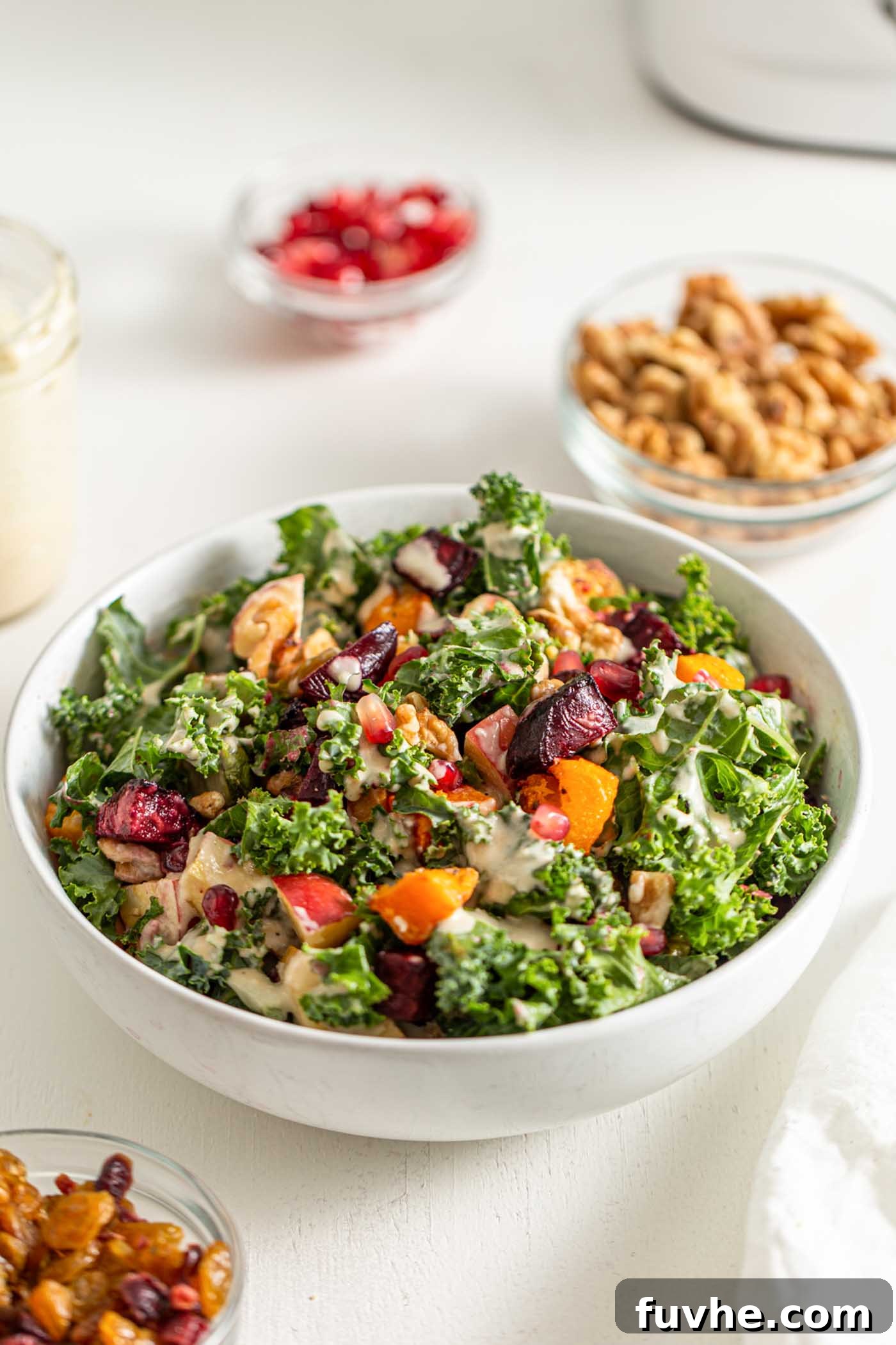 Bowl of kale salad with squash, beets, brussels sprouts, walnuts and pomegranate.