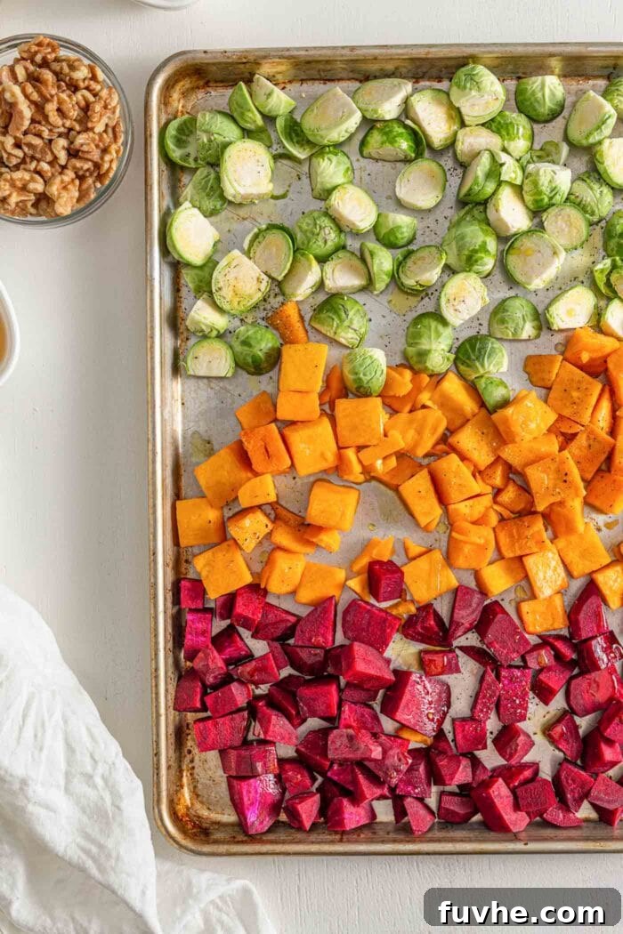 Chopped bussels sprouts, beets and squash on a roasting pan.