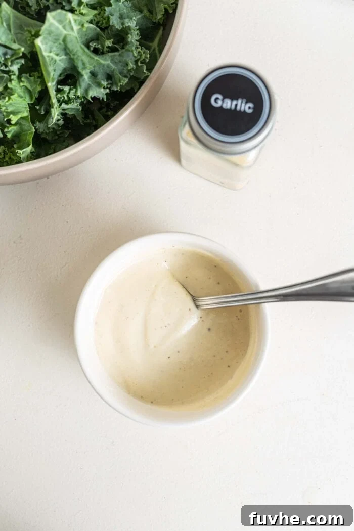 The Ultimate Vegan Kale Caesar 5 Caesar salad dressing in a bowl with a spoon.