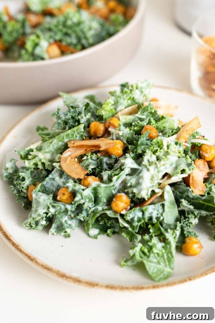 The Ultimate Vegan Kale Caesar 7 Close up of a kale salad on a plate with dressing, coconut bacon and chickpeas.