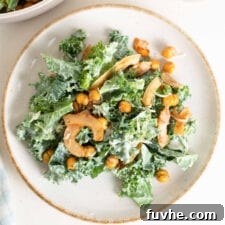 Overhead image of a kale caesar salad with chickpeas and coconut bacon on a plate.