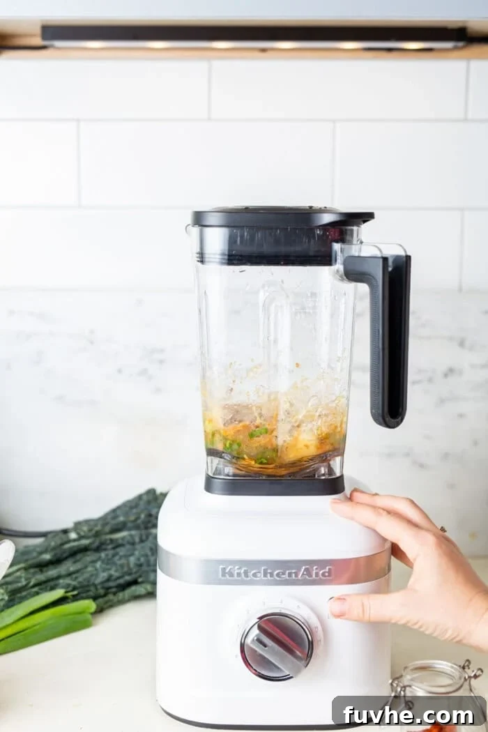 Vibrant Chickpea Kale Stir Fry 4 A high-angle shot of creamy miso peanut sauce being blended smoothly in a white KitchenAid blender.