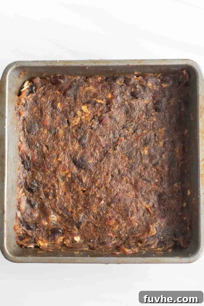 Smooth, evenly spread date paste filling in a baking pan, ready for the top layer.