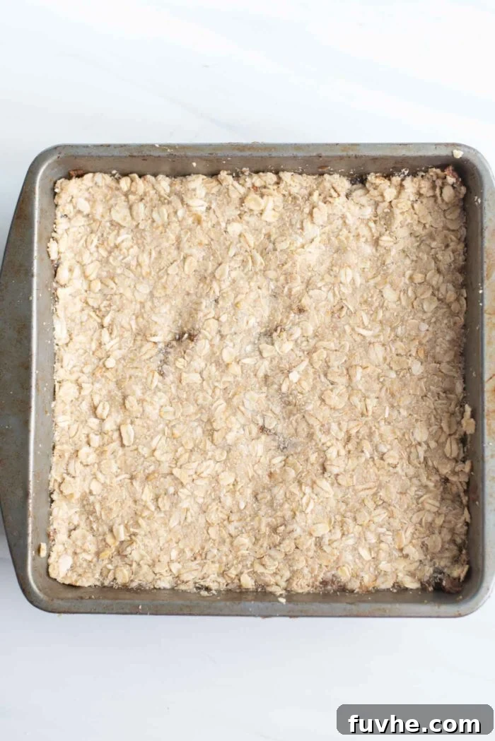 Overhead image of an uncooked, layered oat bar in a baking pan, ready for the oven.
