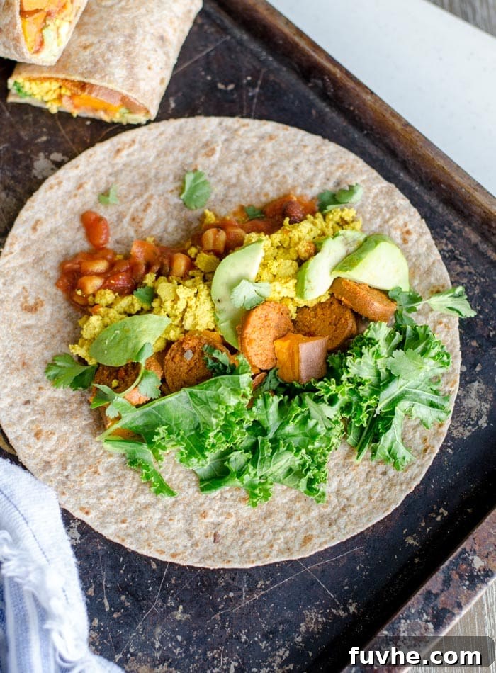 Golden Sweet Potato Burritos 3 Close-up shot of a single vegan sweet potato breakfast burrito, showing a golden-brown tortilla wrapped snugly around a generous filling of sweet potato, tofu scramble, and greens, ready to be enjoyed.