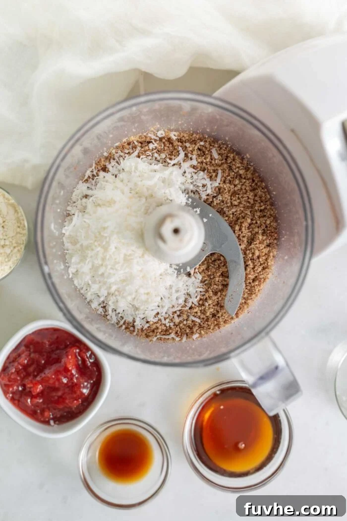 The food processor bowl contains a blend of coconut and pecans, showing the progression of the dough mixture.