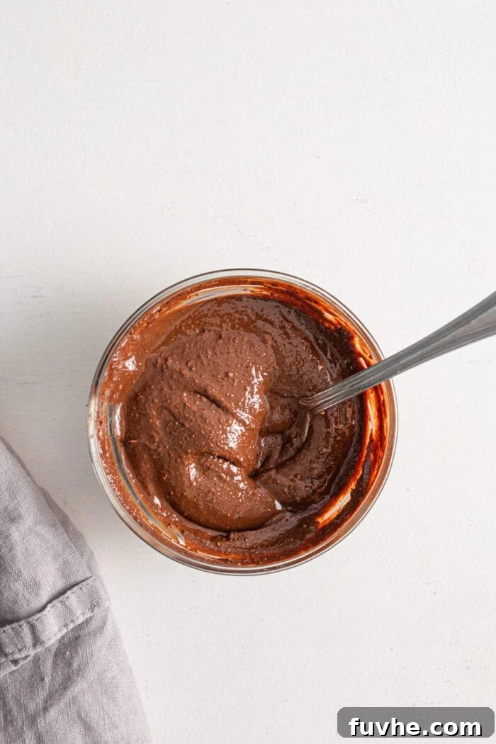Tipsy Vegan Truffles 6 Melted chocolate in a small dish with a spoon resting in it.