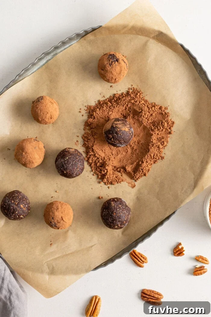 Tipsy Vegan Truffles 8 Chocolate energy balls being rolled in cocoa powder on top of parchment paper.