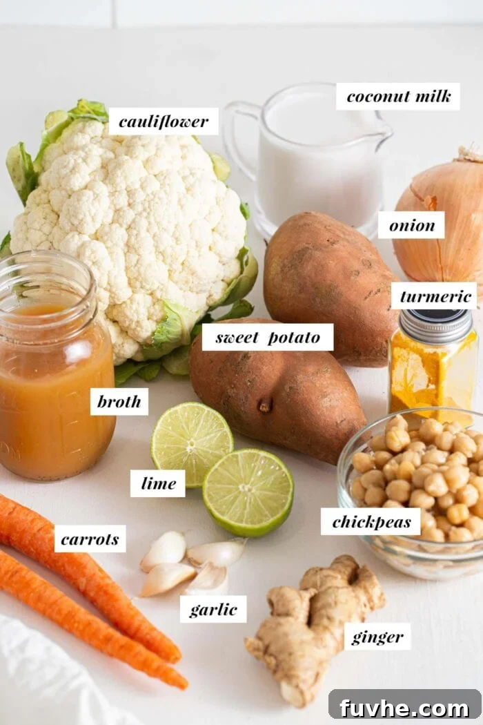 Organized selection of fresh vegetables including sweet potatoes, cauliflower, carrots, ginger, garlic, and onions, ready for making soup.
