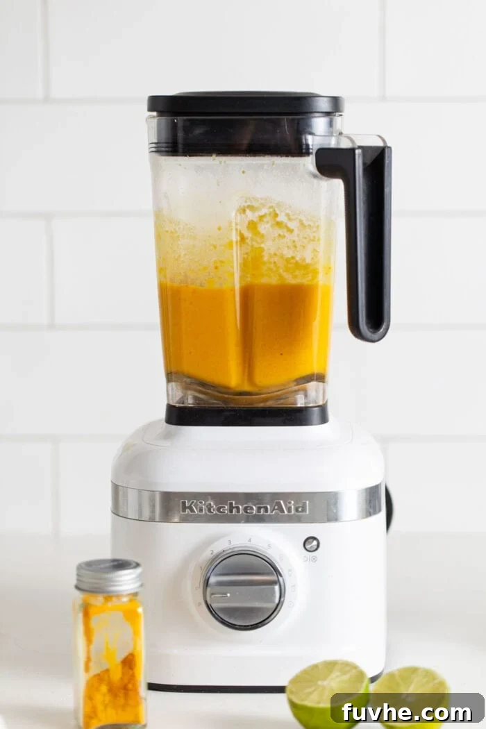 Creamy, blended vegan sweet potato soup in a KitchenAid blender, showing its smooth and rich texture.