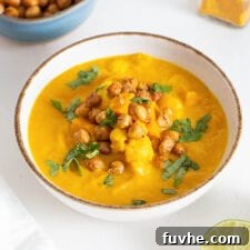 Bowl of sweet potato cauliflower soup topped with chickpeas and cilantro.
