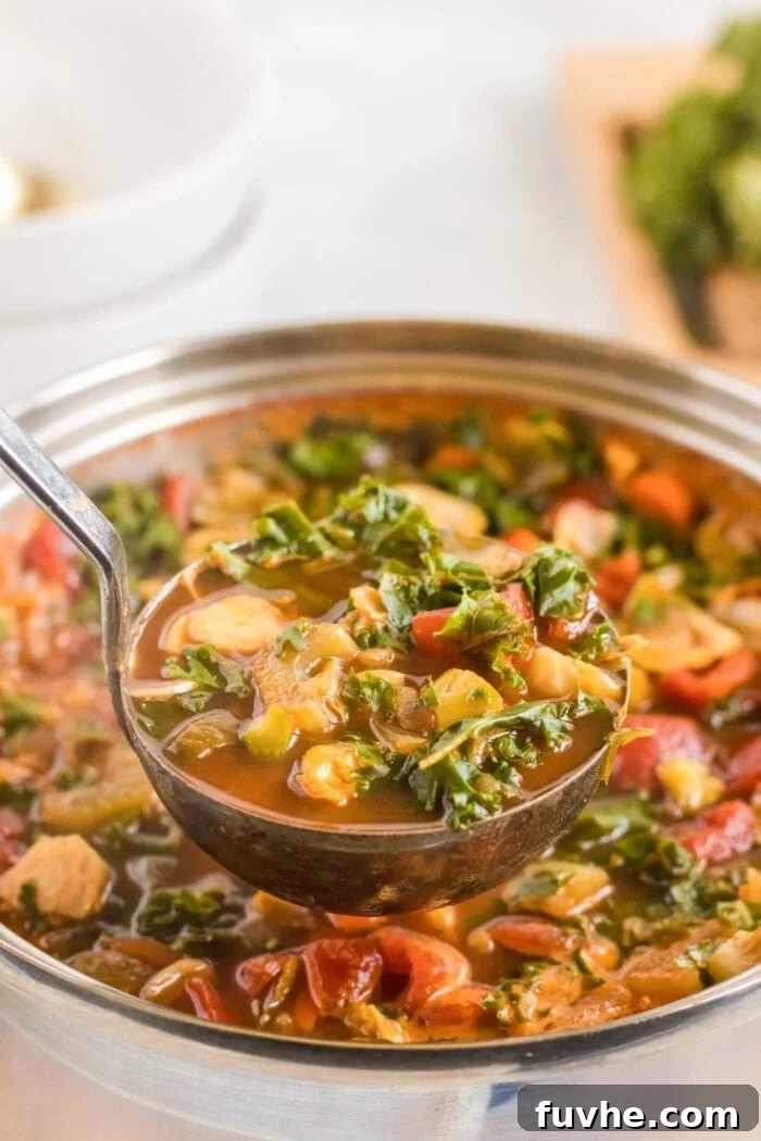 A ladle gracefully scoops a portion of hearty kale and lentil soup from a large, steaming pot, highlighting its rich texture and vibrant ingredients.