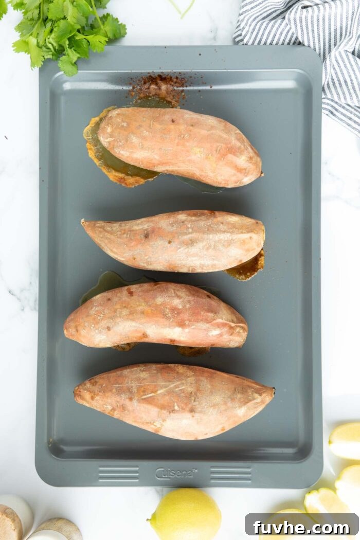 4 baked sweet potatoes on a baking tray.