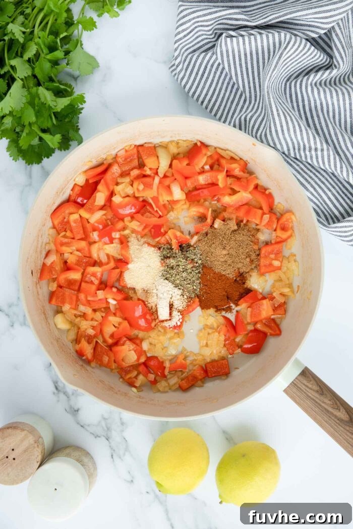 Onion and bell pepper cooking with spices in a large skilet.