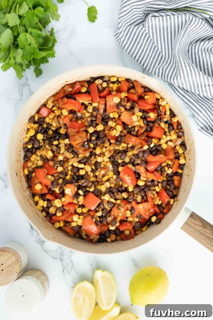 Black beans, corn and bell pepper cooked in spices in a large skillet.