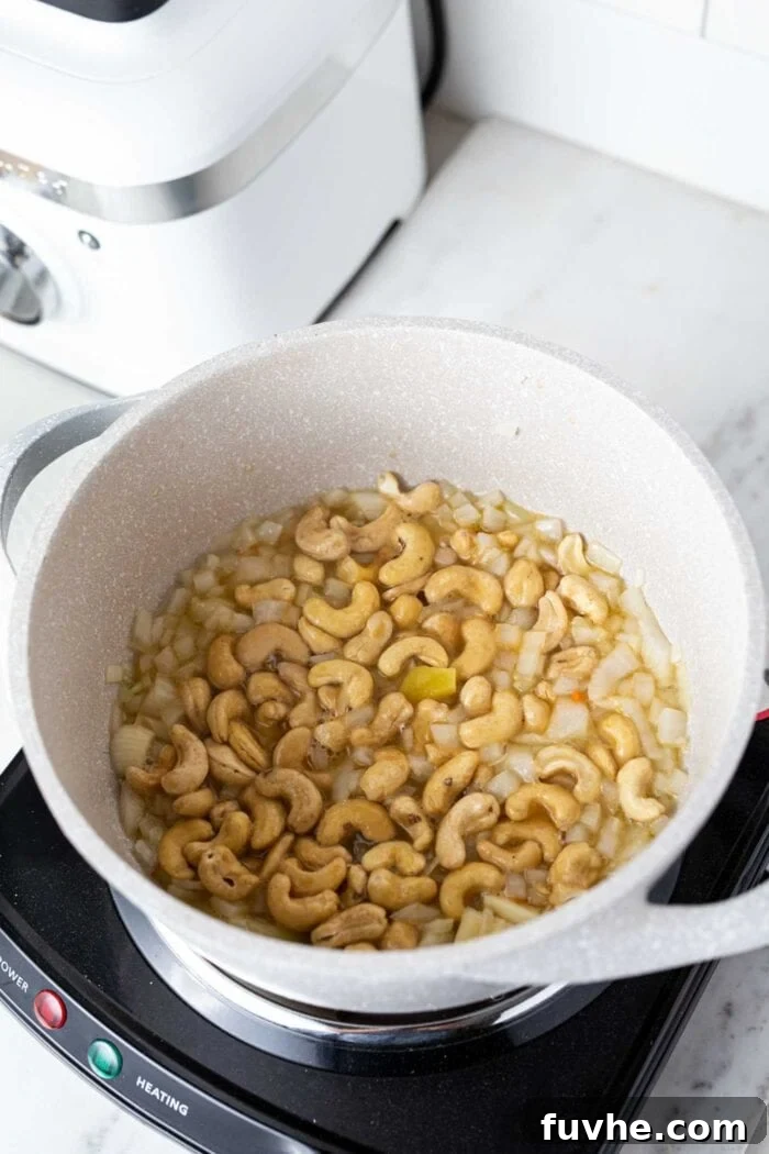 Creamy Golden Cashew Carrot Soup 4 Onions, garlic, ginger, and cashews gently sautéing in a large soup pot.
