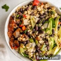 A beautifully presented bowl of vegan black beans and rice, garnished with fresh avocado and salsa.