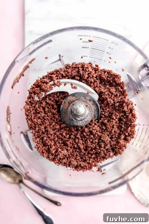 Effortless Chocolate Protein Treats 4 Crumbly chocolate dough in a food processor.