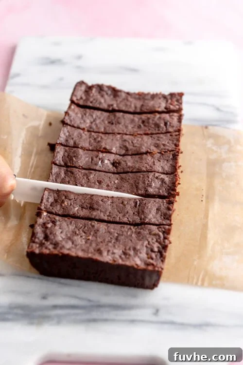 Effortless Chocolate Protein Treats 7 Knife slicing chocolate protein bars into 8 portions on a marble cutting bars.