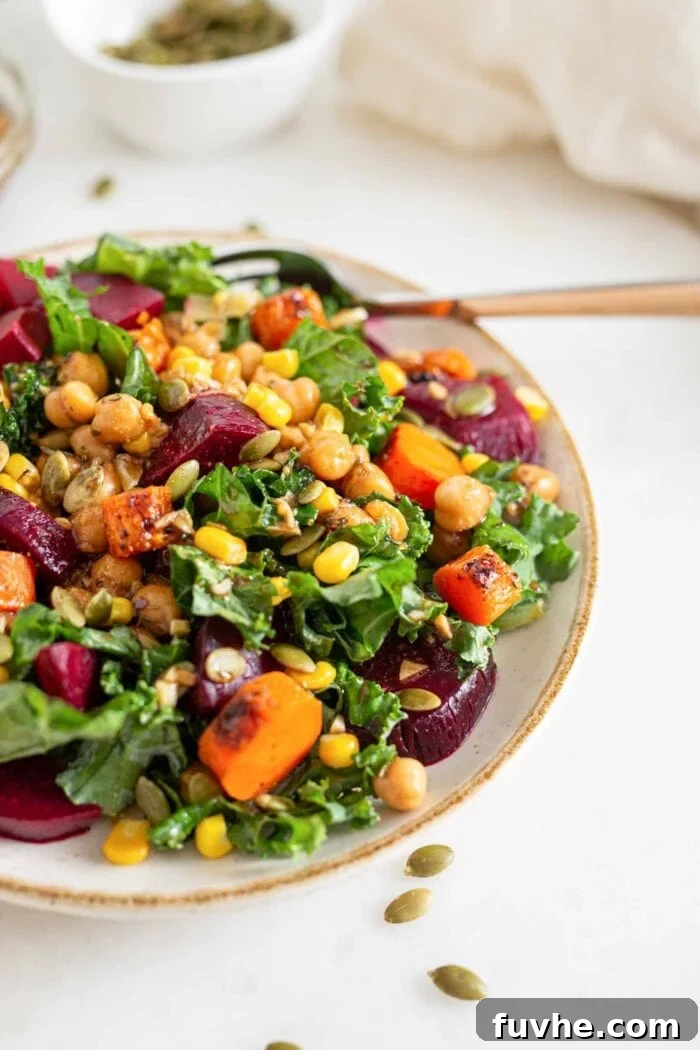 A vibrant bowl of vegan roasted beet kale salad, fully assembled with chickpeas, roasted carrots, tender beets, and sweet corn, ready to be enjoyed.