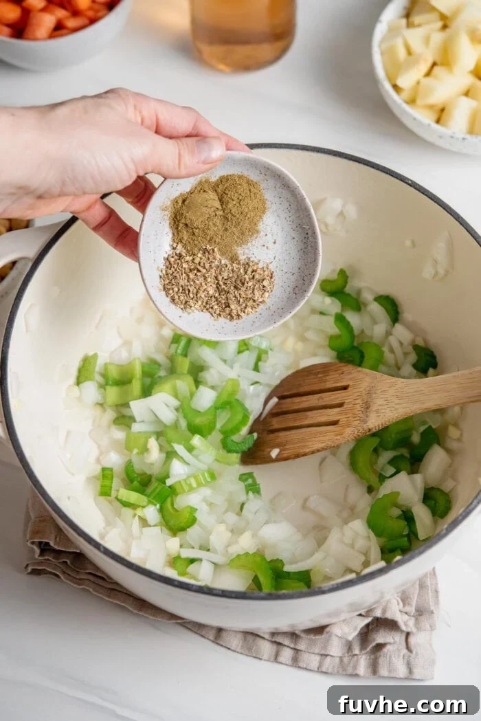 Adding a small dish of dried herbs to celery and onion cooking in a pot.