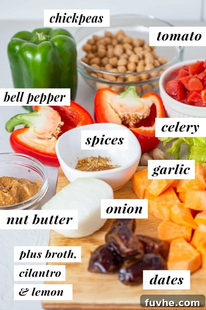 A flat lay photograph of various fresh ingredients laid out, including onions, celery, bell peppers, garlic, sweet potatoes, chickpeas, and a jar of peanut butter, all prepared for making a sweet potato peanut stew.