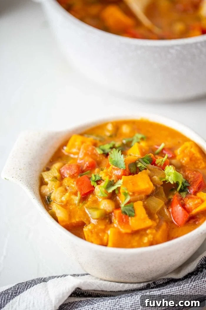 A beautiful bowl of vegan sweet potato peanut stew, garnished generously with fresh green cilantro, ready to be enjoyed as a wholesome and delicious meal.