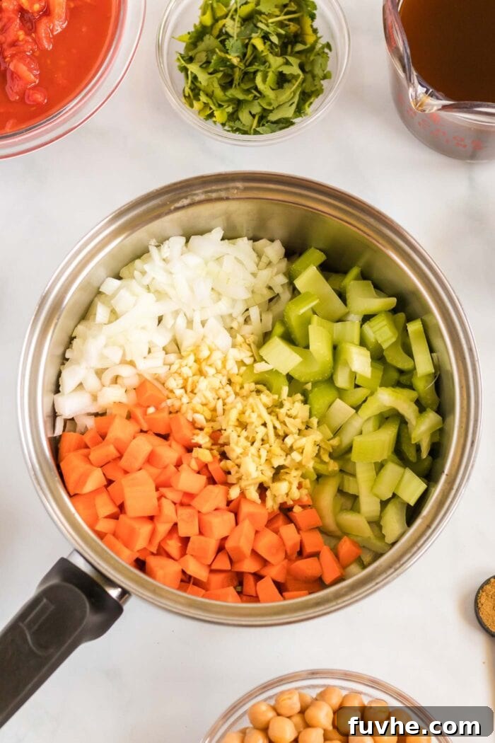 Finely diced celery, onion, garlic, and carrot gently sautéing in a large soup pot, forming the aromatic and flavorful base of the stew.