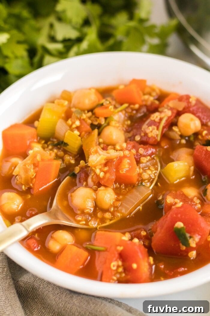 Close-up view of a vibrant, steaming bowl of chickpea quinoa stew, generously garnished with fresh cilantro, ready to be savored.