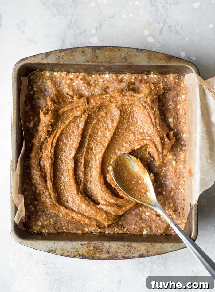 Effortless Vegan Peanut Butter Blondies 6 Spreading peanut butter frosting evenly over a pan of blondies, creating a smooth top layer.
