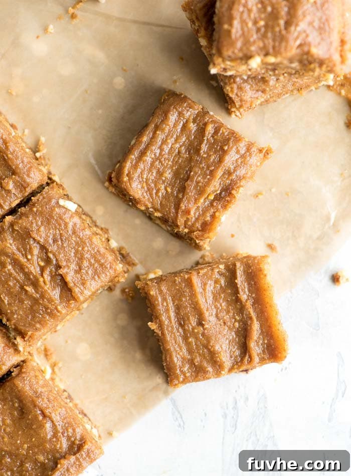 Effortless Vegan Peanut Butter Blondies 7 Overhead view of several perfectly sliced peanut butter blondies with their creamy frosting, arranged on parchment paper.