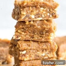 Close up of a stack of 4 peanut butter dessert bars topped with a thick layer of peanut butter frosting, visually enticing and delicious.