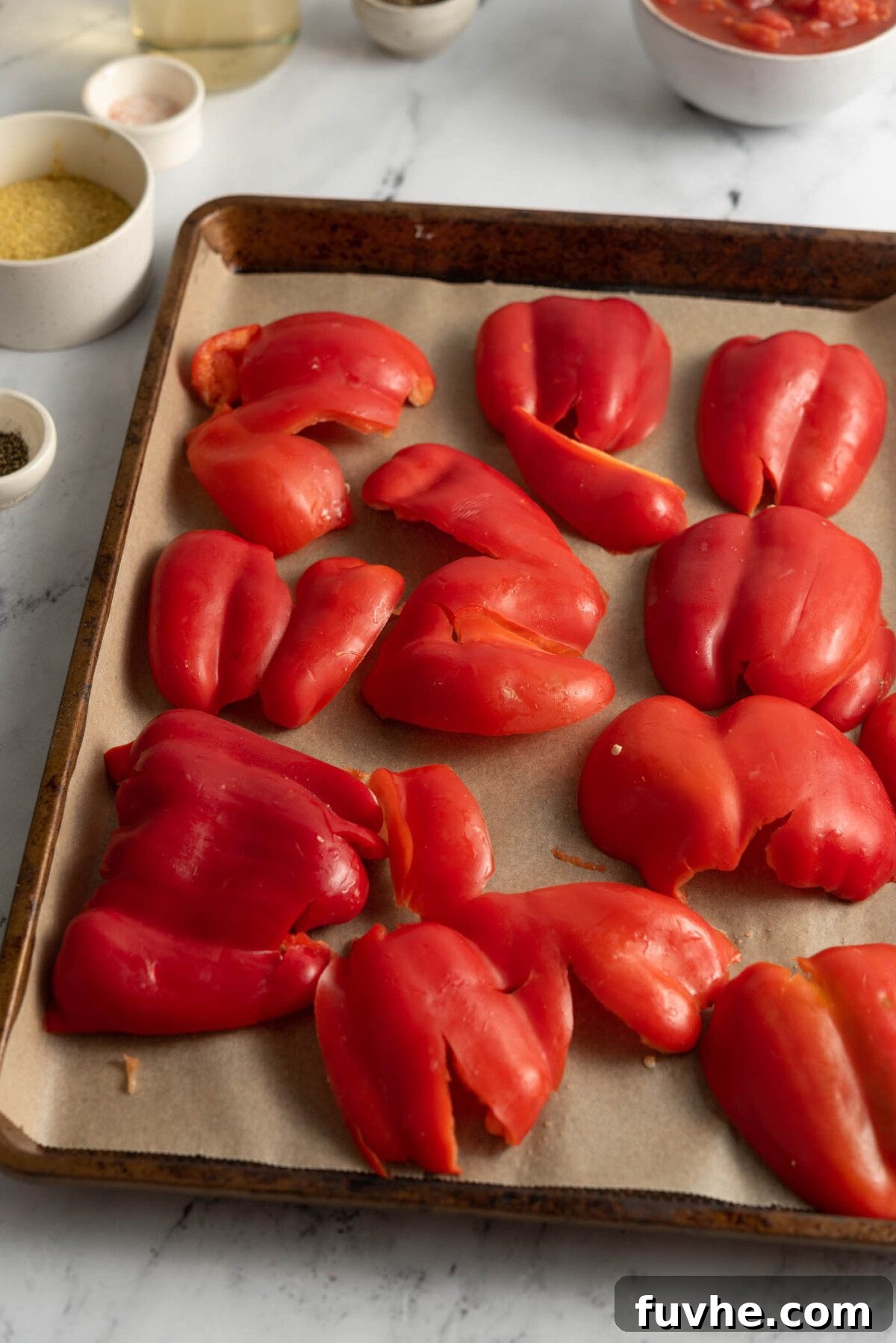 Bell peppers meticulously arranged and flattened on a baking tray, ready for the roasting process to unlock their sweet, smoky potential.