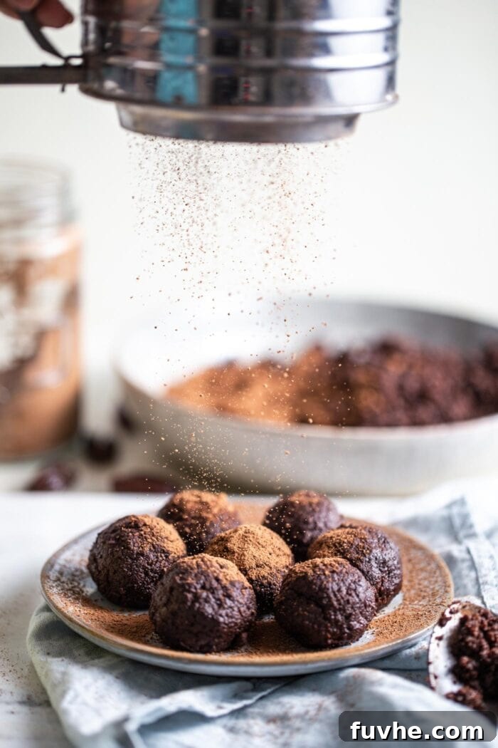 Sweet Swaps from Nature 13 Chocolate date energy balls sitting on a plate being dusted with cocoa powder.