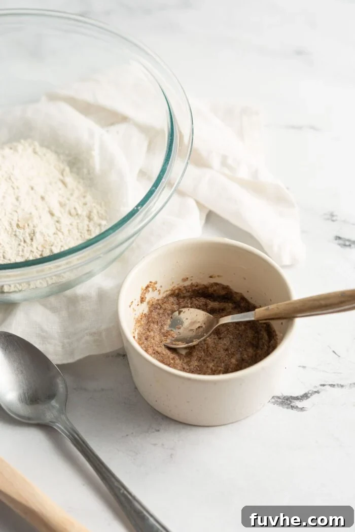 Protein-Packed Vegan Quinoa Pancakes 4 A flax "egg" in a small dish with a spoon. Bowl of flour is behind the dish.