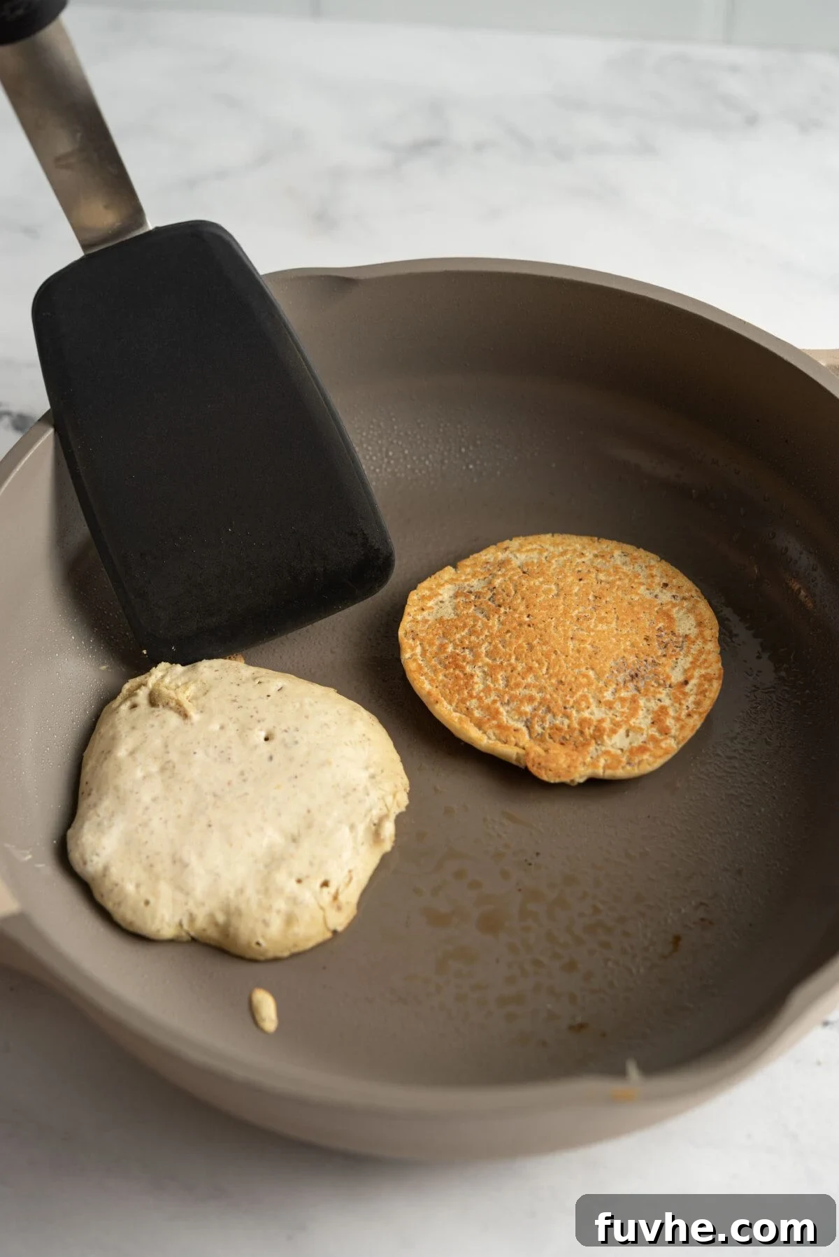 Protein-Packed Vegan Quinoa Pancakes 6 Spatula flipping a pancake in a hot skillet.